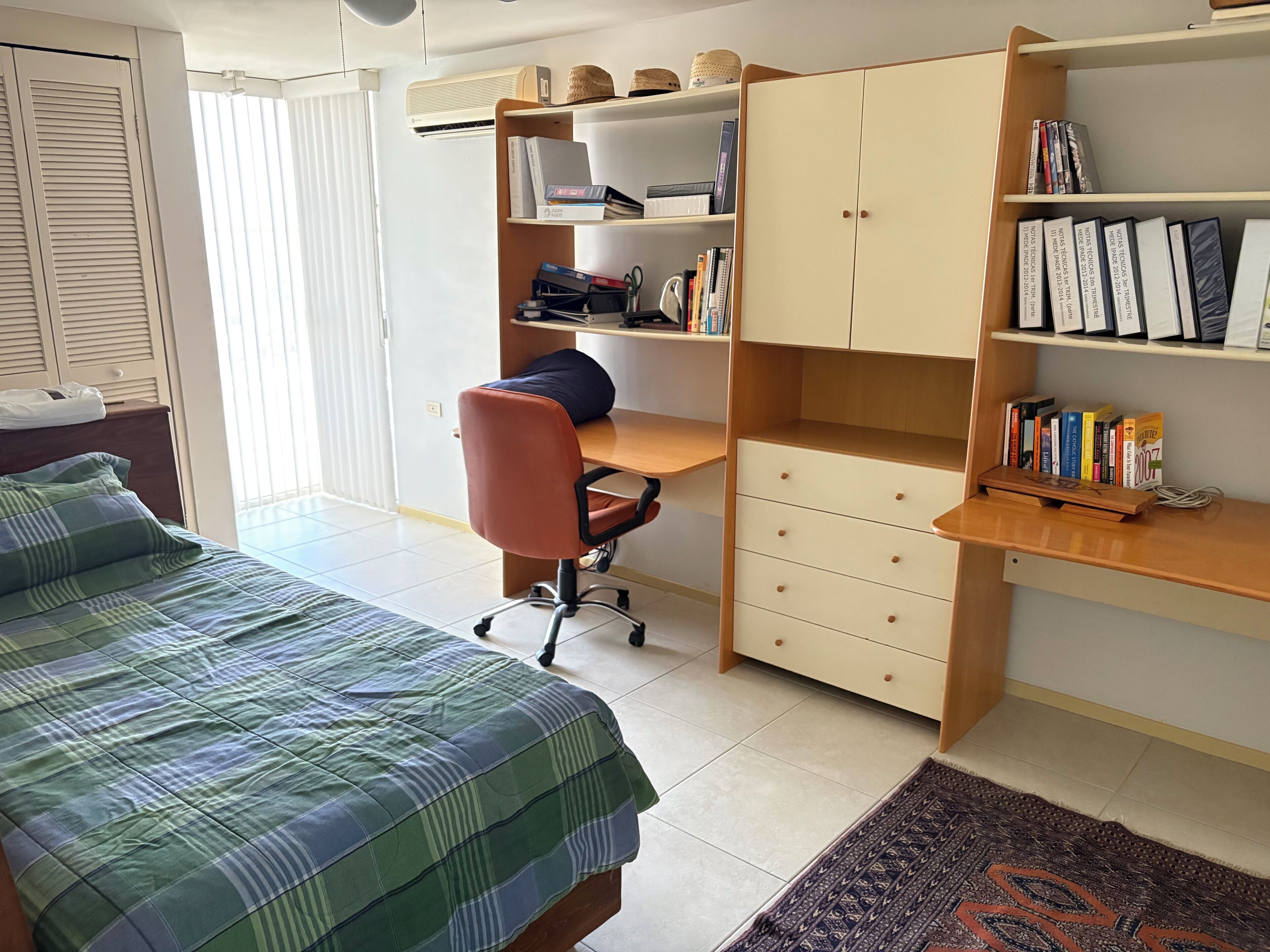 Una camera da letto con un letto, una scrivania, una sedia, una libreria e un armadio.