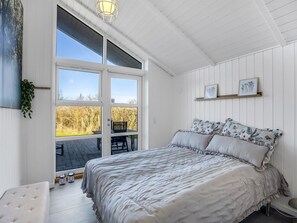 Ein Schlafzimmer mit einem großen Bett, einem Fenster, einem kleinen Tisch und einer Bank.