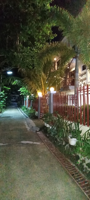 A nighttime view of a gated entrance with a pathway leading to a building. - Layanglayang Home (El Nido)