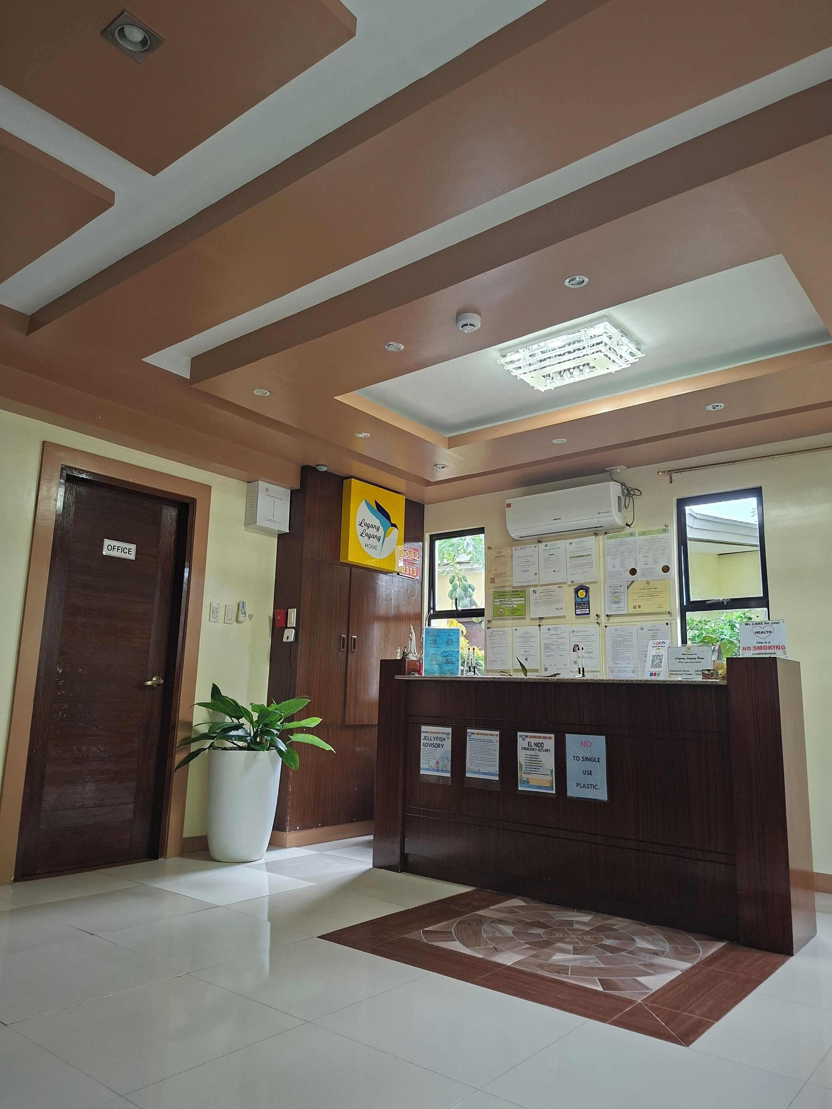 A reception area with a wooden desk, a potted plant, and a tiled floor.