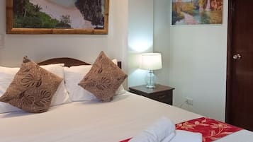 Ein Hotelzimmer mit einem großen Bett, zwei Kissen, einem Nachttisch mit einer Lampe, einem Bild an der Wand und einer Tür.