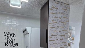 Eine moderne Küche mit einer Spüle aus Edelstahl, einem eingebauten Backofen und einer wandmontierten Mikrowelle.