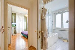 Quarto de hotel com cama, banheiro com banheira e vista para o exterior.