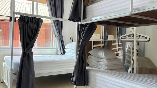 Quarto com beliche, janela, cortinas e uma pequena mesa.