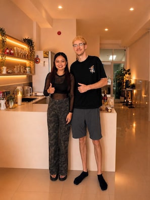 A modern hotel lobby with a reception desk, a glass partition, and a decorative plant. - Behome and hostel (Chiang Mai)