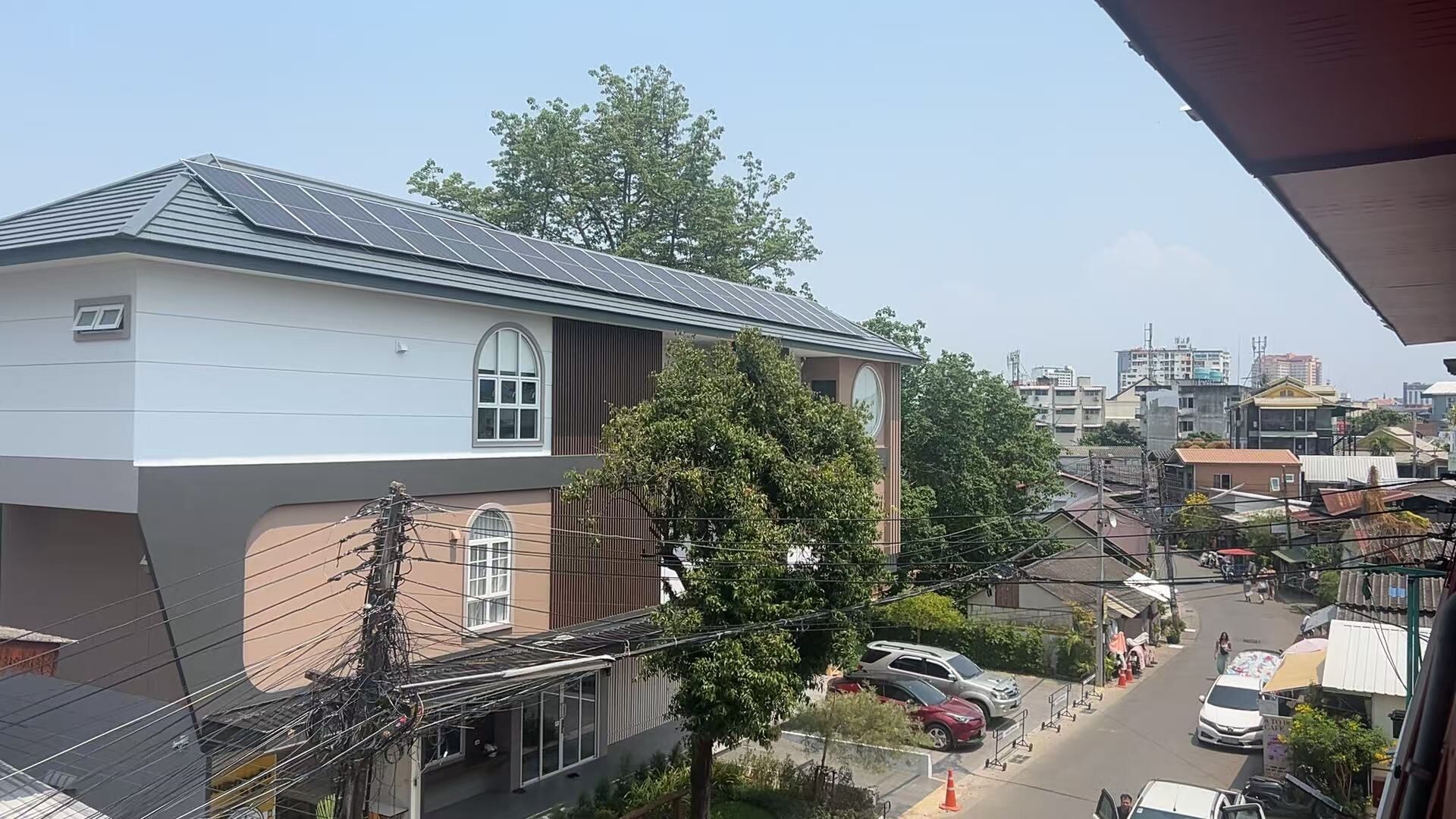 A residential building with a sloped roof, large windows, and visible power lines.