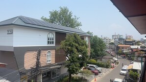 Um edifício residencial com telhado inclinado, janelas grandes e linhas de energia visíveis.