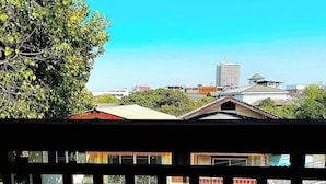 Vista de uma paisagem urbana com edifícios, céu claro e uma área de estacionamento com carros.