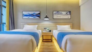 A hotel room with two beds, a nightstand, and artwork on the walls.