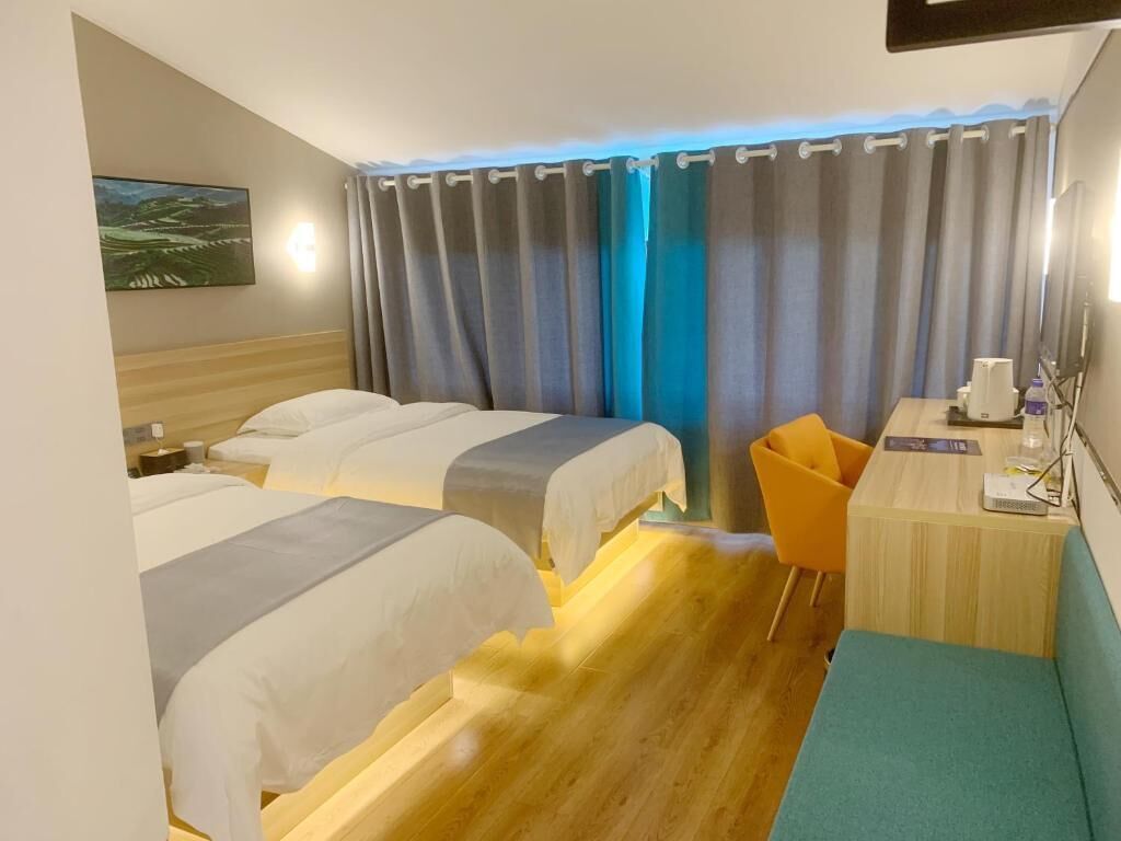 Una habitación de hotel con dos camas, un escritorio, una silla y una cortina.