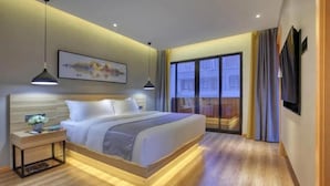 Un dormitorio moderno con una cama grande, mesitas de noche, un televisor y una ventana con cortinas.