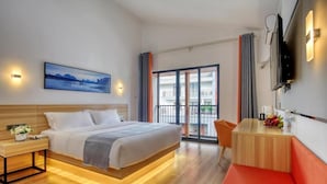 Una habitación de hotel moderna con cama, mesita de noche, televisión y un balcón con cortinas.