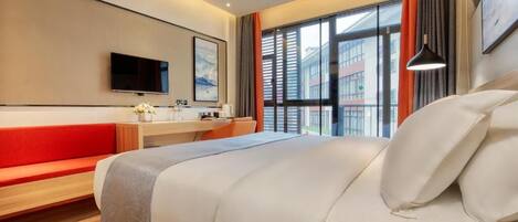 A modern hotel room with a bed, a desk, a TV, and a window with blinds.