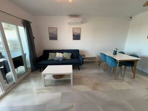 Ein modernes Wohnzimmer mit einer Couch, einem Couchtisch, einem Esstisch mit Stühlen und einer Schiebetür aus Glas.