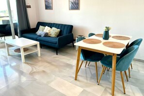 Ein modernes Wohnzimmer mit einer Couch, einem Couchtisch, einem Esstisch mit Stühlen und einer Vase mit Blumen.