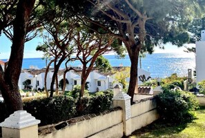 Une propriété située sur la côte, avec des bâtiments blancs, un mur de pierre et une vue sur la mer.