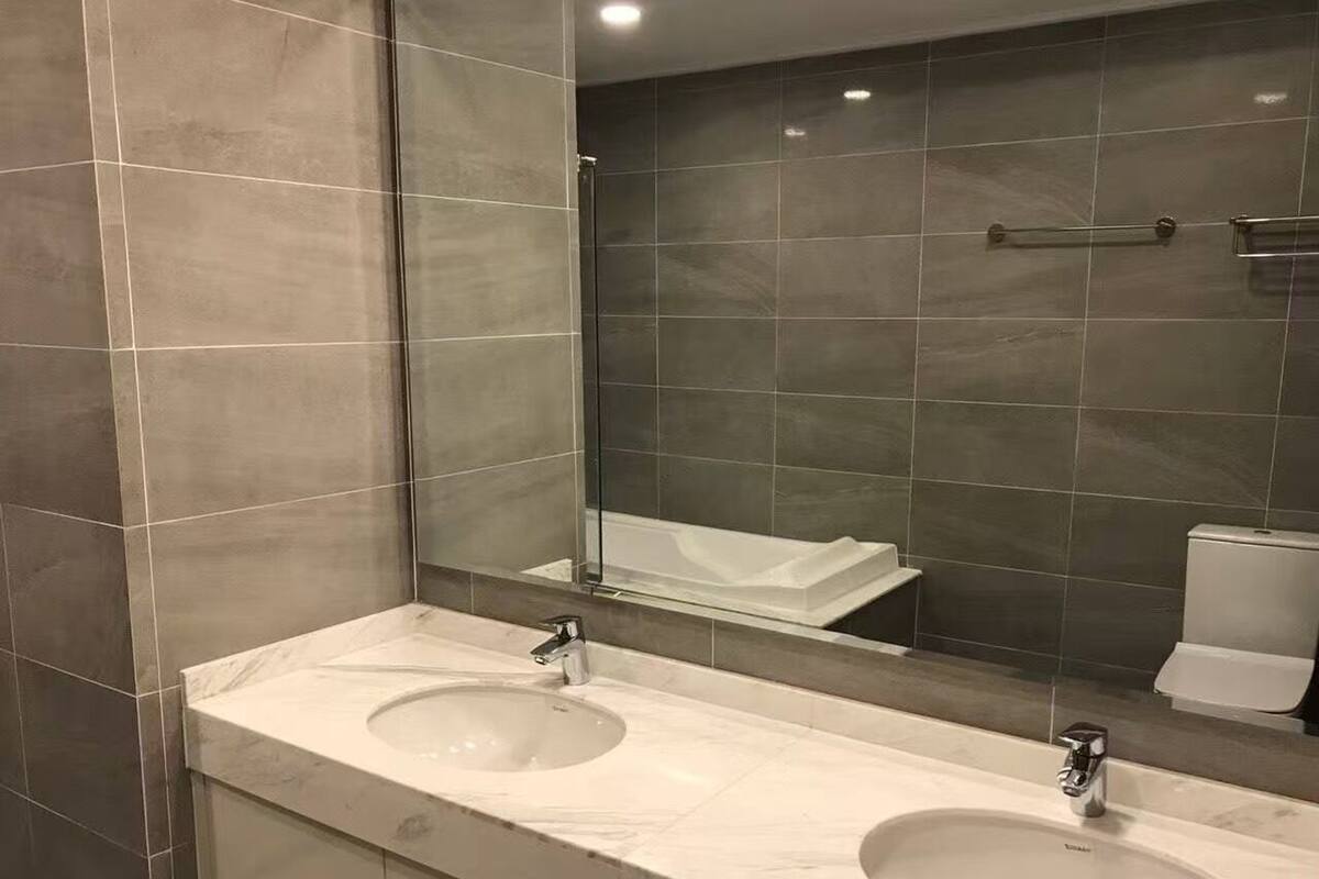 A bathroom with two sinks, a large mirror, and a toilet.