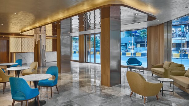 A modern lobby with round tables and chairs, large windows, and a view of the street outside. - AUREA  (Phnom Penh)