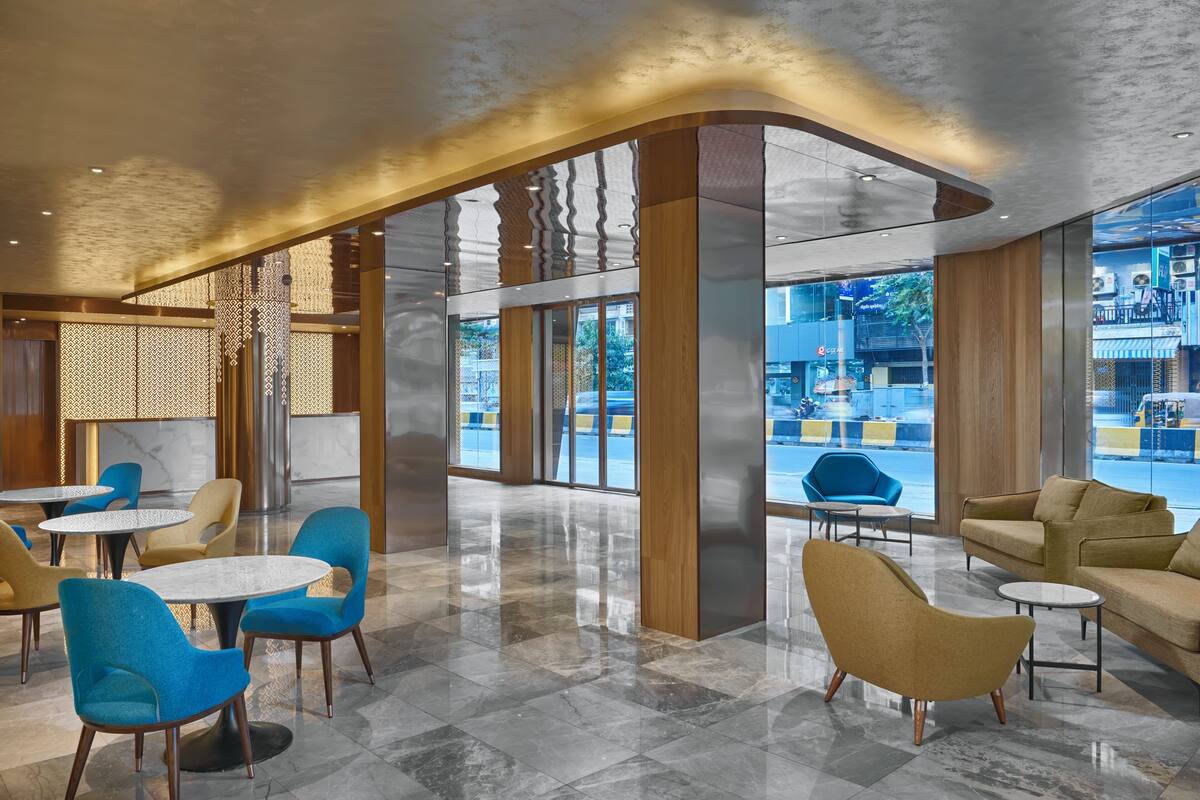 A modern lobby with round tables and chairs, large windows, and a view of the street outside.
