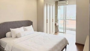 Une chambre à coucher comprenant un lit, une armoire et une porte-fenêtre coulissante donnant sur un balcon.