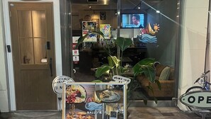 Un escaparate con un letrero que dice 'Nalu no' y un expositor con menús y un código QR.