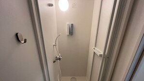 Un cuarto de baño estrecho con una puerta blanca, un secador de manos y un perchero para toallas.