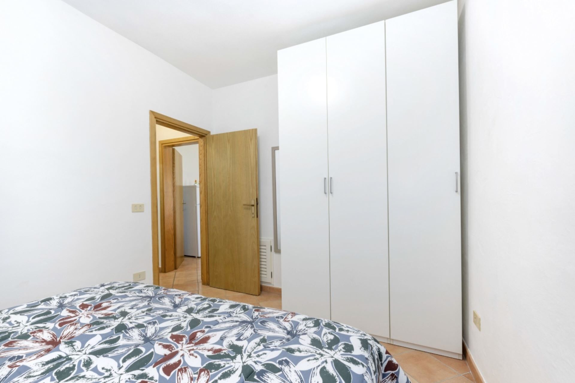 Un dormitorio con cama, armario y espejo.