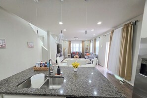 Eine moderne Küche mit Granit-Arbeitsplatten, einer eingebauten Spüle und einem Essbereich mit weißem Tisch und Stühlen.