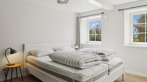 A white bed with a headboard, a bedside lamp, and a window with a view of trees. - "Farah" - 25km from the sea by Interhome (Skærbæk)