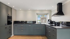 A modern kitchen with grey cabinets, a large island, and a black range hood. - "Farah" - 25km from the sea by Interhome (Skærbæk)