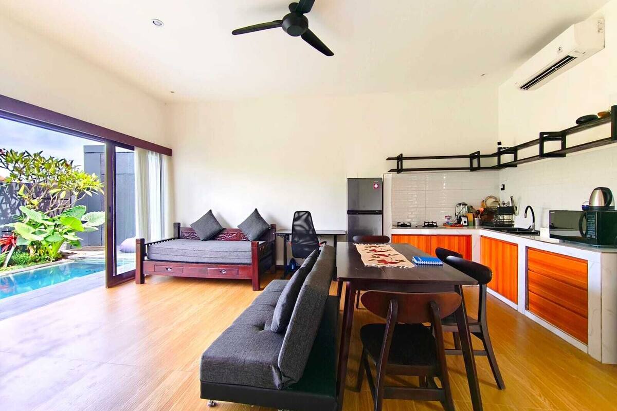 Ein modernes Wohnzimmer mit Essbereich, Küche und Blick auf einen Pool.