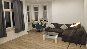En stue med en brun sofa, et glasbord, et spisebord med stole og en lampe.