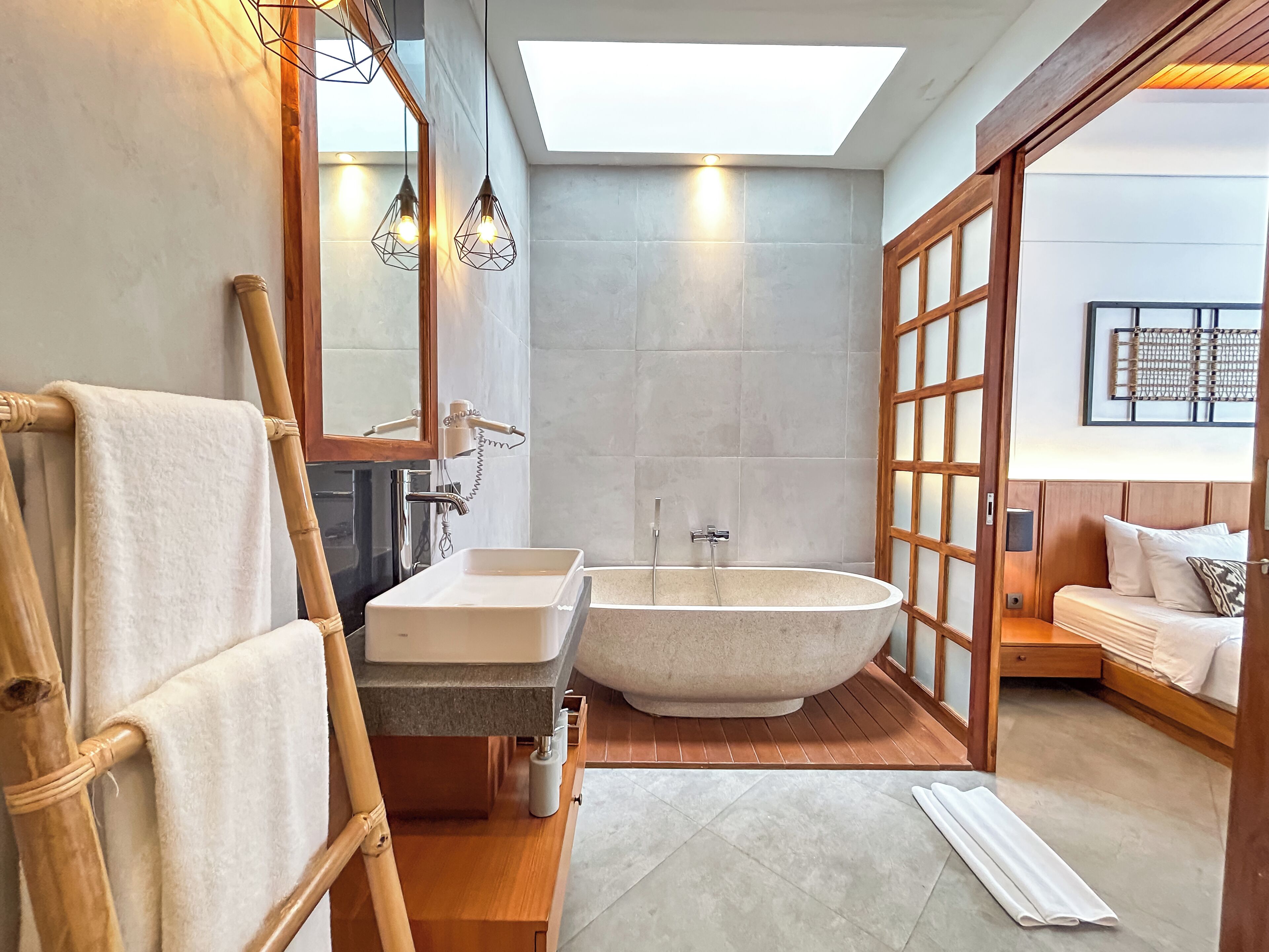 A modern bathroom with a freestanding bathtub, a vanity with a mirror, and a towel rack.