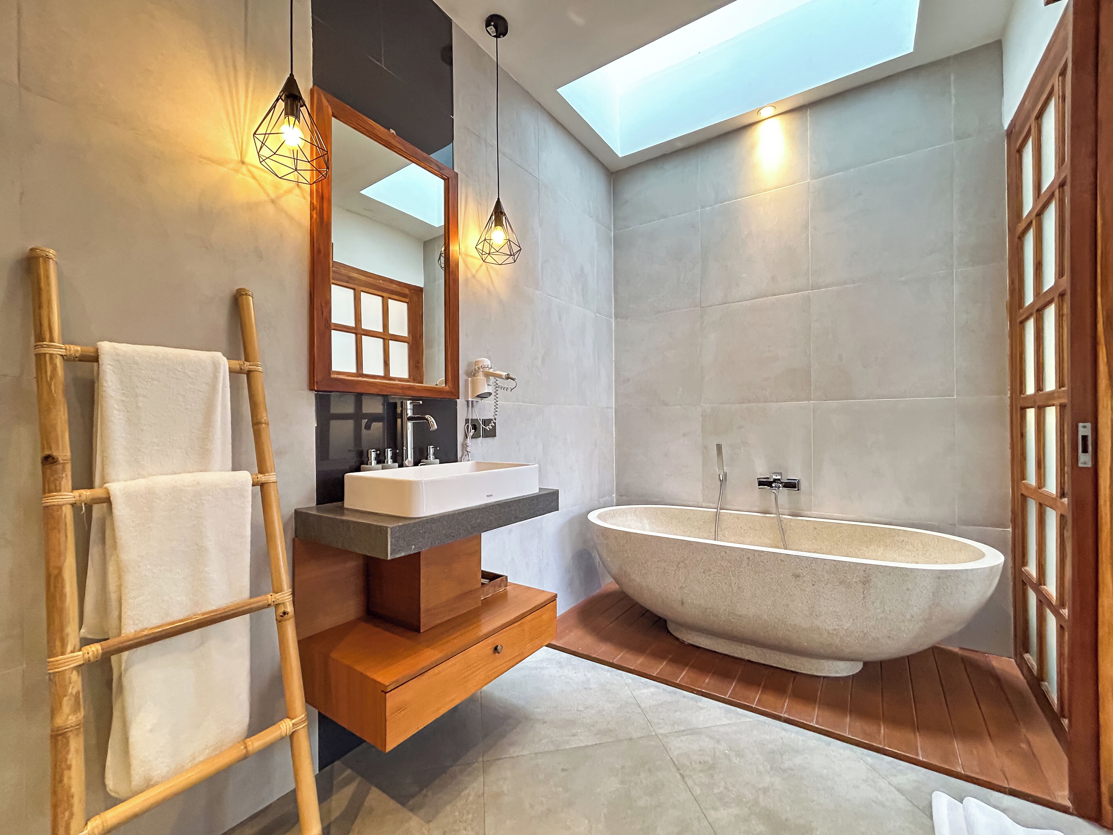 A modern bathroom with a freestanding bathtub, a vanity with a mirror, and a towel rack.