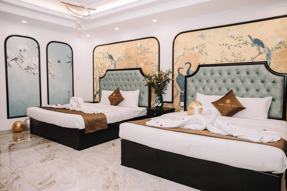 Ein Hotelzimmer mit zwei Betten, jeweils mit einem gebuschten Kopfteil, weißer Bettwäsche und dekorativen Kissen.