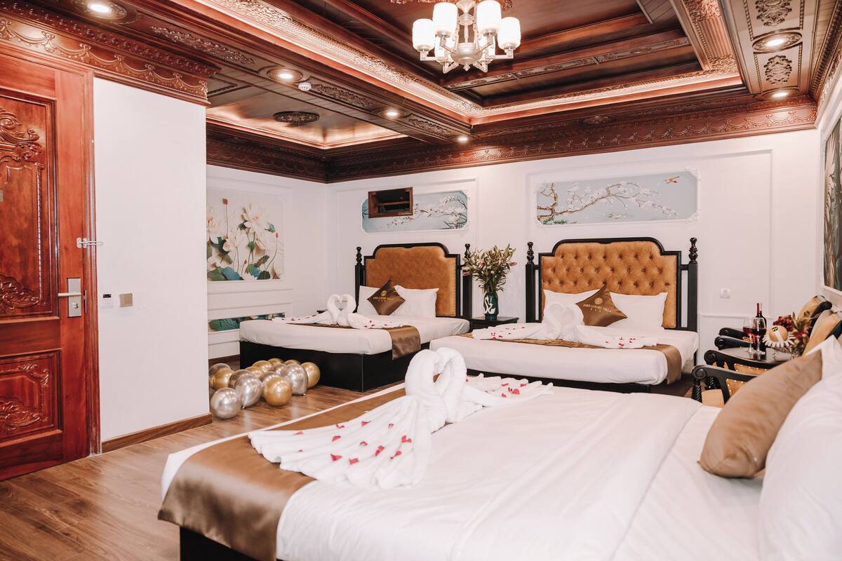 Ein Hotelzimmer mit zwei Betten, einer Holztür und einer Chandelüstere.
