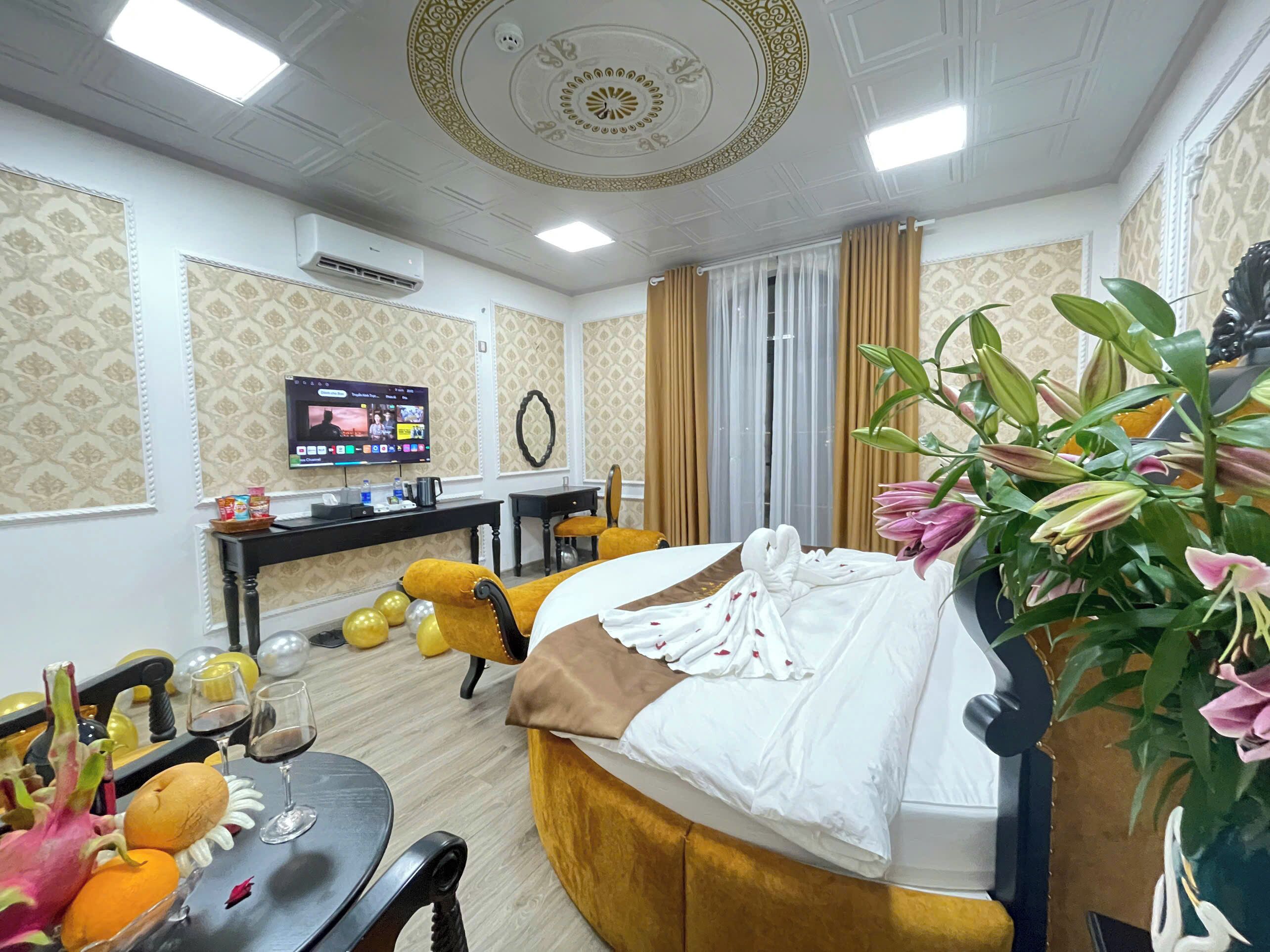 A hotel room with a bed, a desk, a television, and a plant.