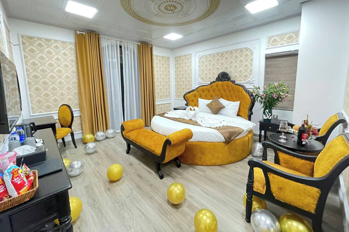 Ein Hotelzimmer mit einem großen Bett, zwei Sesseln, einem Schreibtisch und einem kleinen Tisch.