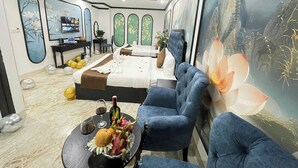 Quarto de hotel moderno com uma cama grande, um sofá, uma TV e uma parede com um mural de tema natural.