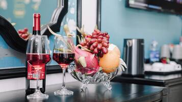 Une bouteille de vin, deux verres et un panier de fruits sur une table.