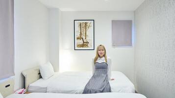 Camera d'albergo con un letto, un comodino, un quadro appeso al muro e una finestra con una tenda.