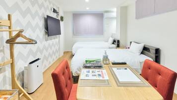 A hotel room with two beds, a TV, a heater, a table with a menu, and a coat rack.