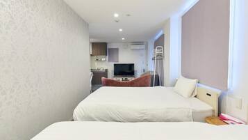 A hotel room with a bed, a TV, a kitchenette, and a window.