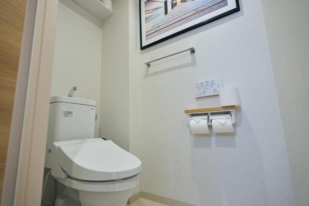 A small, clean bathroom with a toilet, a hand dryer, and a paper towel dispenser.