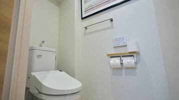 A small, clean bathroom with a toilet, a hand dryer, and a paper towel dispenser.