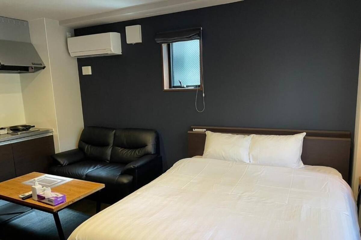 Ein Hotelzimmer mit Bett, Sessel, kleinem Tisch, Klimaanlage und Fenster.