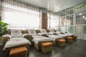 A spa room with multiple massage tables, each with a white cover and a pillow. - Shengshi Fengqing Boutique Inn (Zhangjiajie)