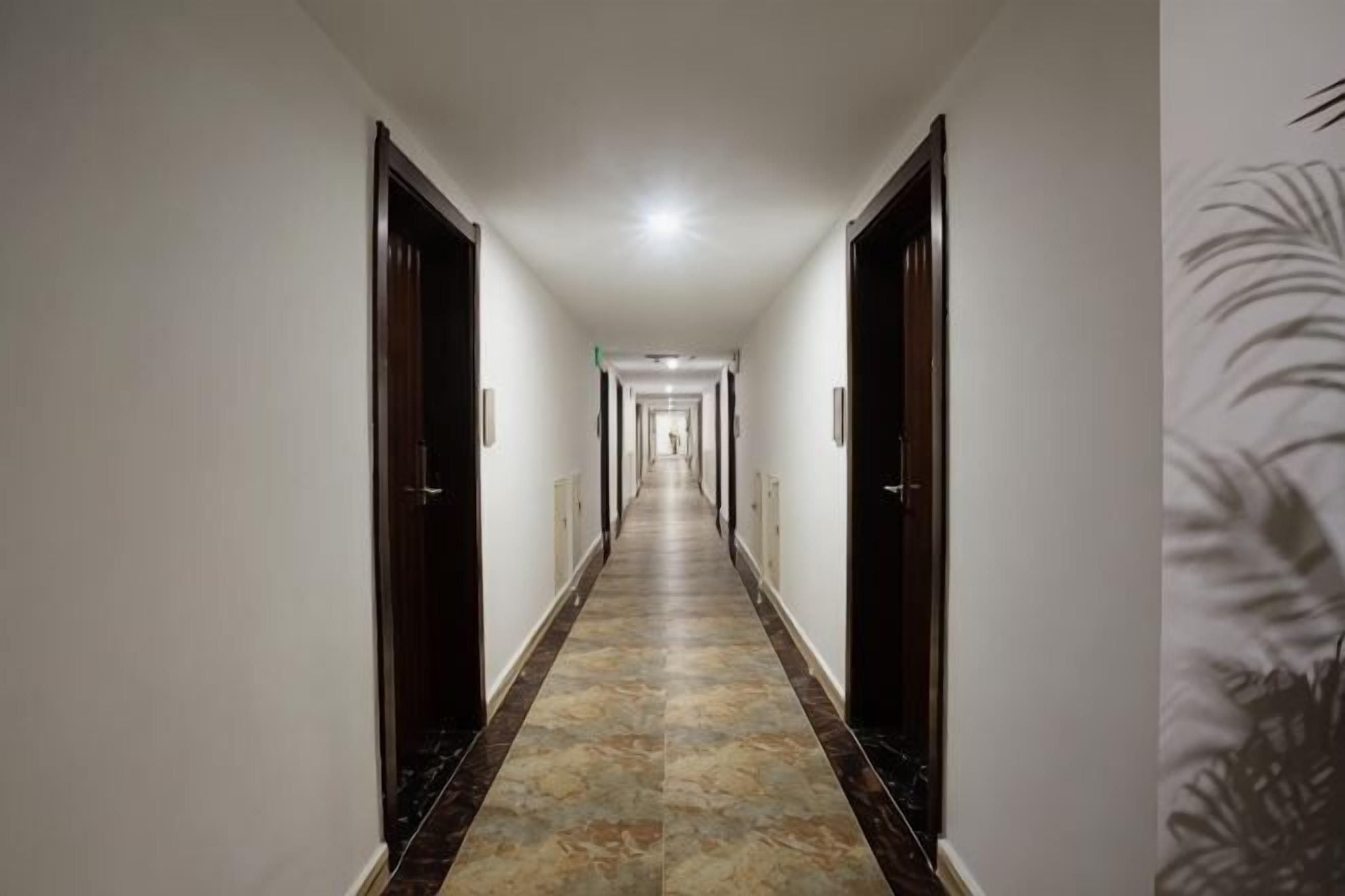 Un long couloir étroit, avec des portes de part et d’autre, qui mène à un espace lumineux à l’extrémité.