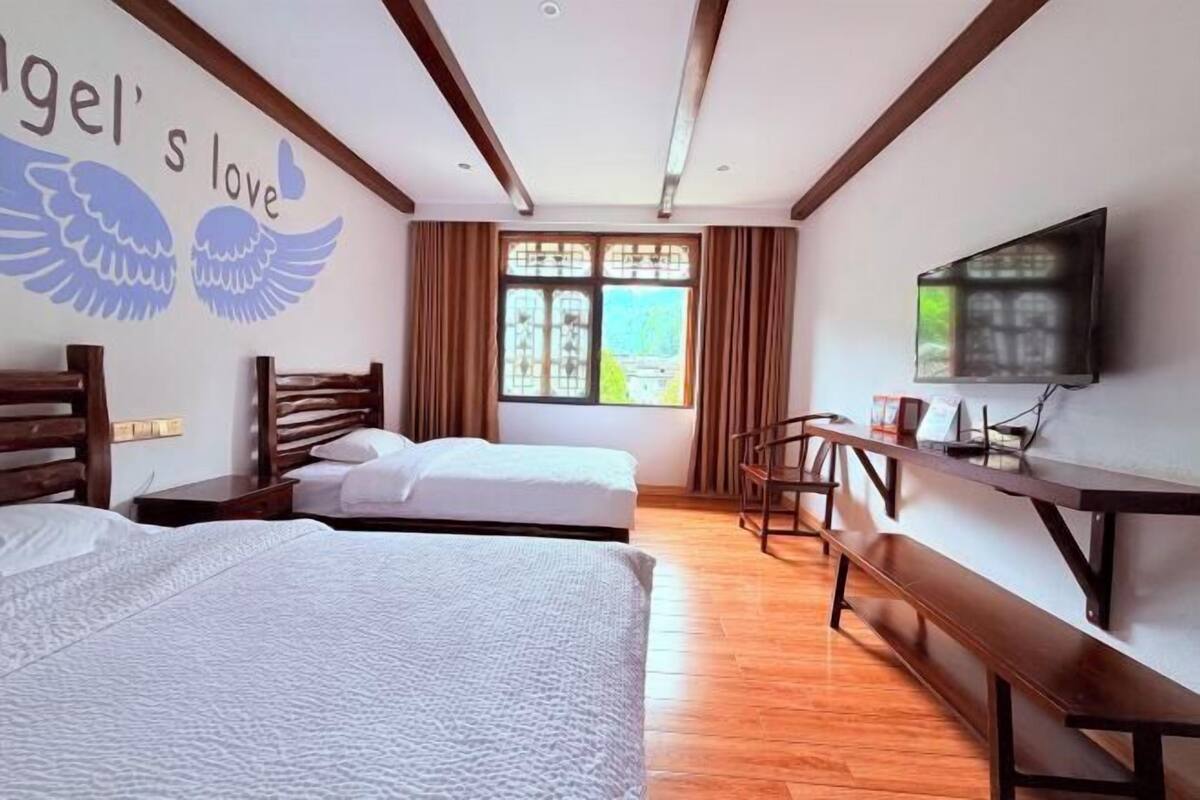 Une chambre d’hôtel avec deux lits, une télévision, un bureau et une fenêtre avec des rideaux.