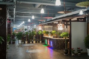 A corridor with potted plants, a reception area with a counter, and hanging lights. - Shengshi Fengqing Boutique Inn (Zhangjiajie)